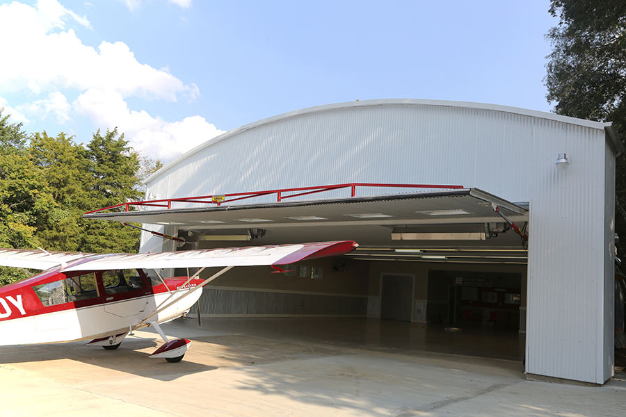 Red plane outside hanger with hydraulic door